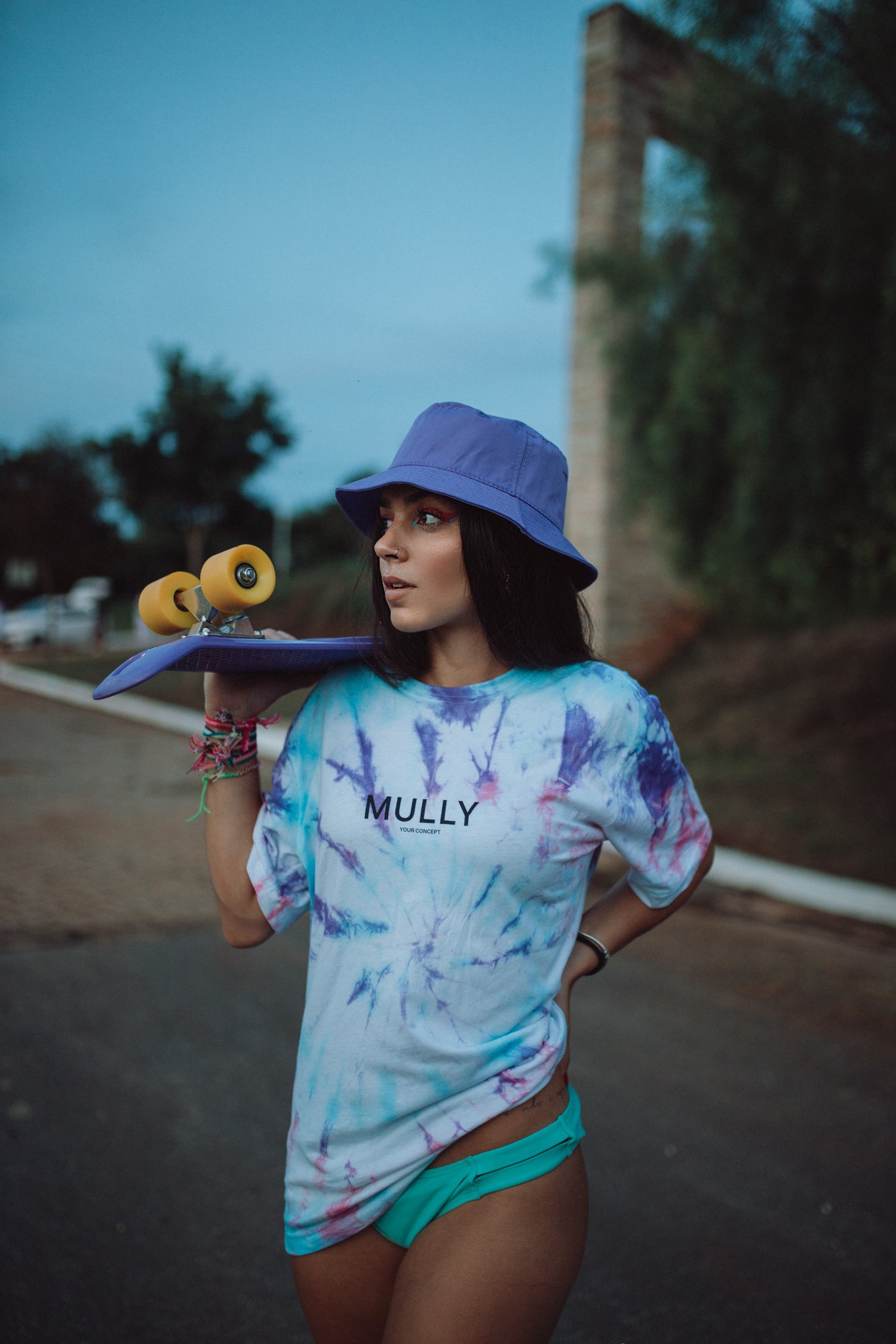 Woman wearing purple bucket hat holding a skateboard