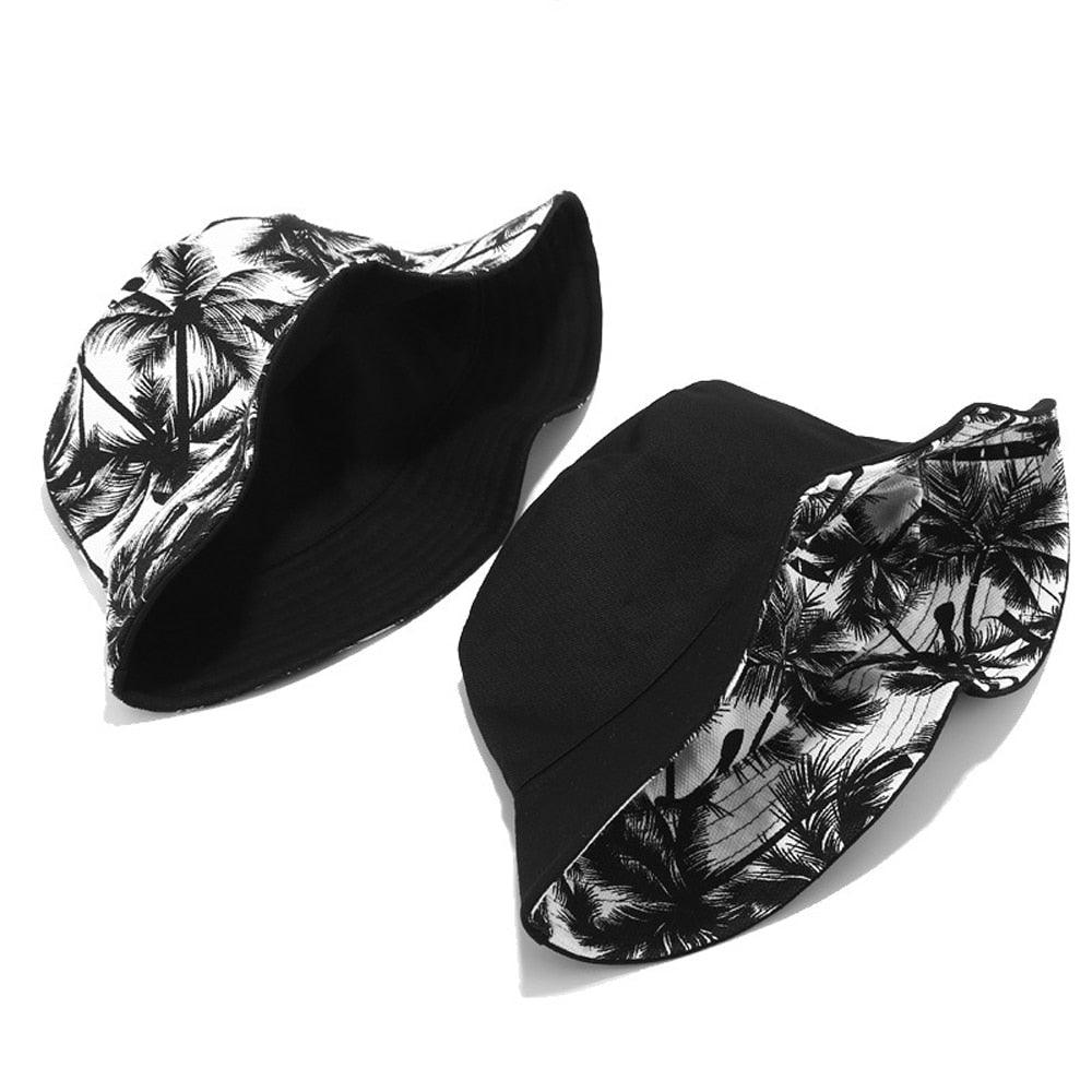 Two bucket hats with black and white palm trees on it.