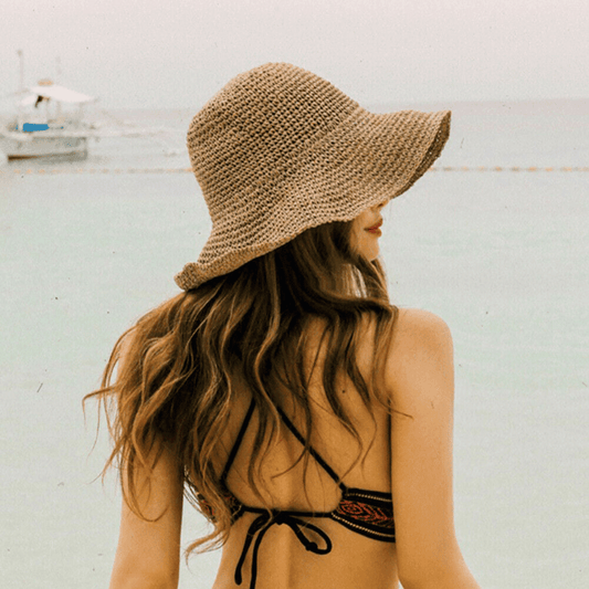 Woman wearing floppy straw sun hat at nz beach